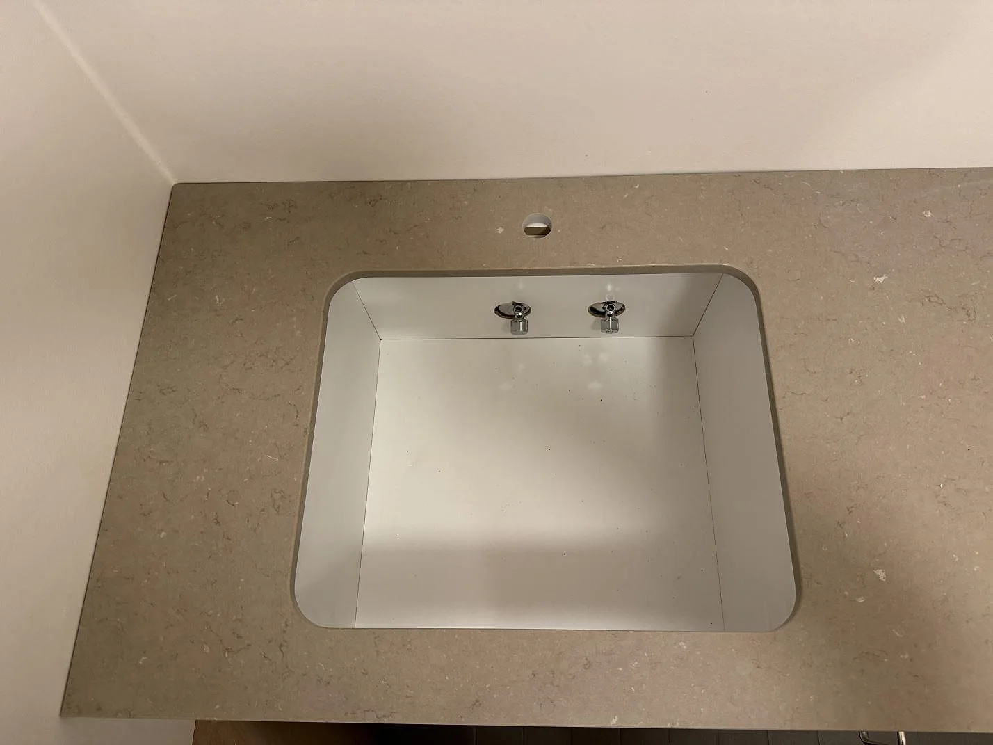 Närbild på förberett diskhourtag i Silestone Coral Clay, polerad kompositbänkskiva monterad mot vägg i Svendborg.