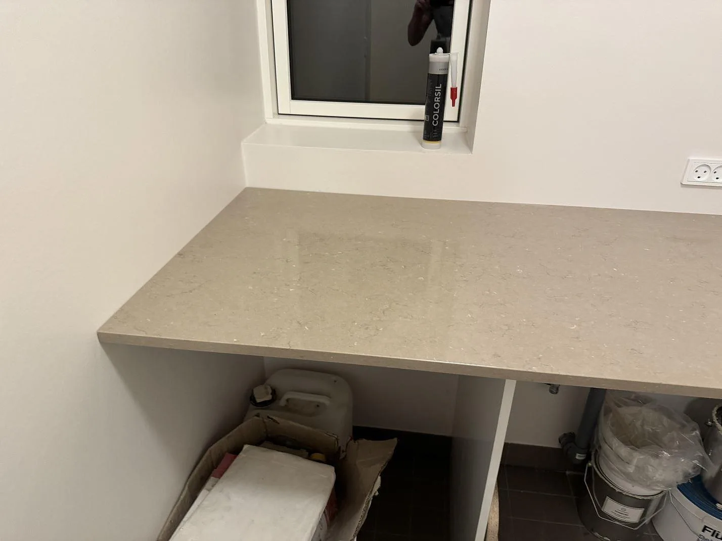 Bänkdel i polerad Silestone Coral Clay under fönster, varm gråbeige komposityta monterad i Svendborg.