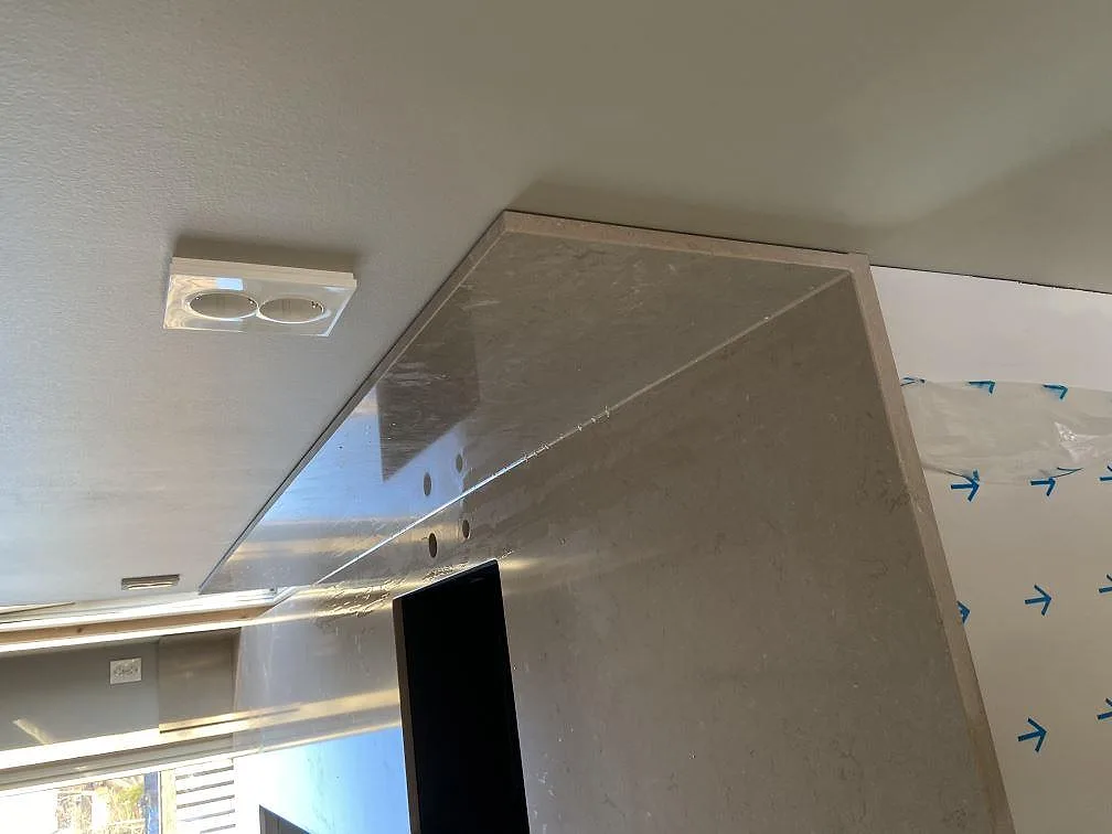 Polerad Silestone Coral Clay bänkskiva med uppvikt stänkkant i hörnet av ett kök under montering i Tenhult.