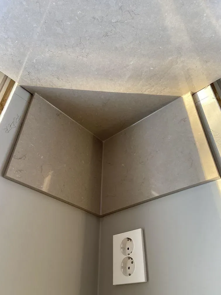 Köksbänkskiva i Silestone Coral Clay med uppvikt stänkkant och vägguttag under montering i ett kök i Tenhult.