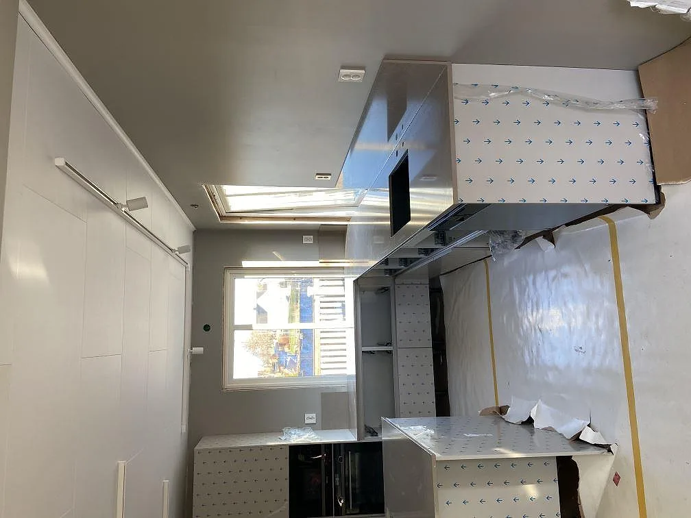 Ljust kök under montering med köksbänkskivor i Silestone Coral Clay vid fönstret och köksö i Tenhult.