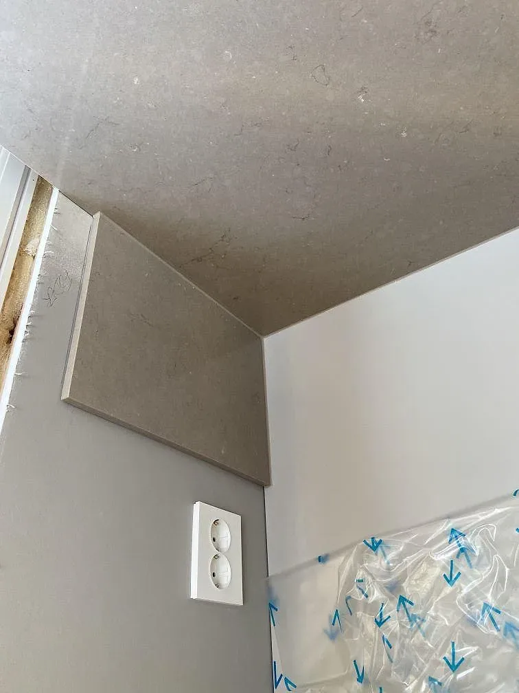 Detalj av polerad Silestone Coral Clay bänkskiva med uppvikt stänkkant under montering i ett kök i Tenhult.