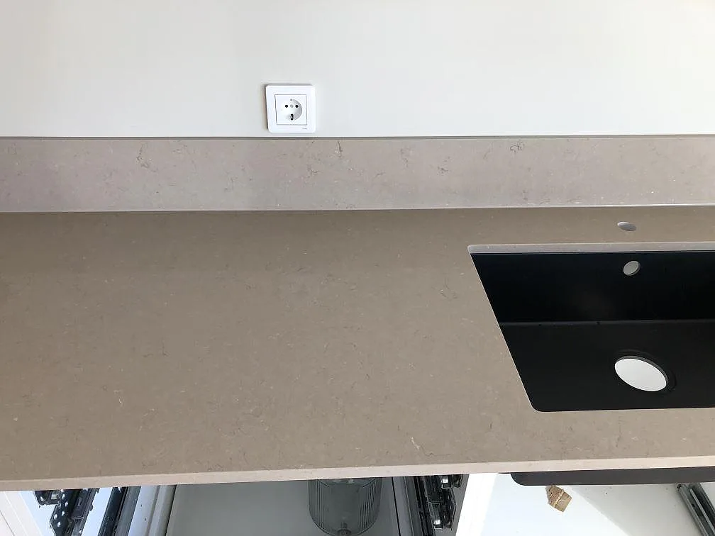 Svart underlimmad kompositdiskho med kran- och avloppshål i en Silestone Coral Clay köksbänkskiva i Trelleborg.