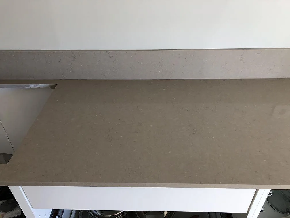 Närbild ovanifrån på den varma greige ytan och stänkkanten på en Silestone Coral Clay köksbänkskiva i Trelleborg.