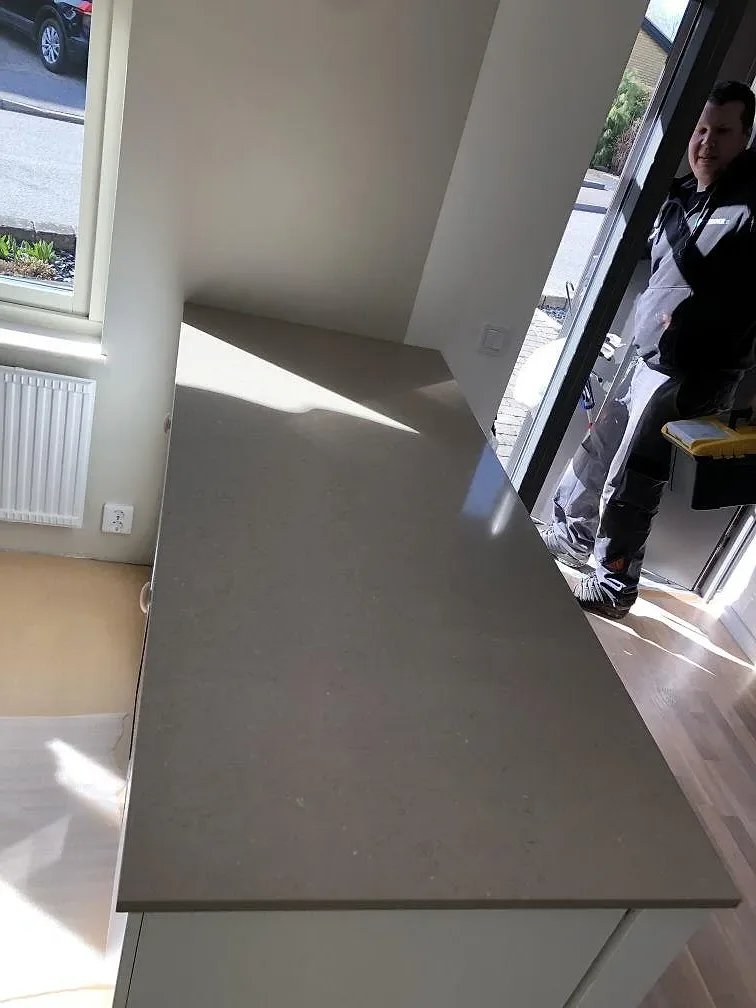 Greige Silestone Coral Clay köksbänkskiva på en köksö i ett kök under montering i Trelleborg.