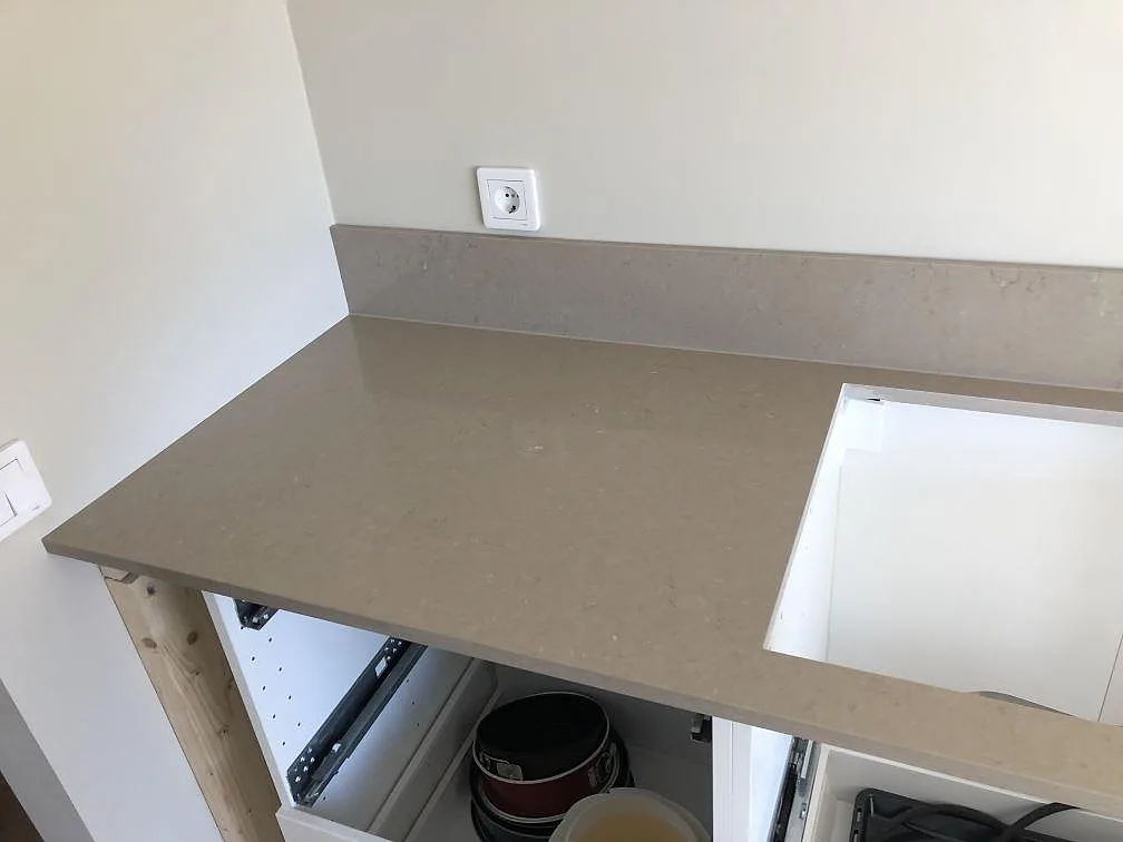 Köksbänkskiva i Silestone Coral Clay med uppvikt stänkkant över öppna lådstommar under montering i ett kök i Trelleborg.