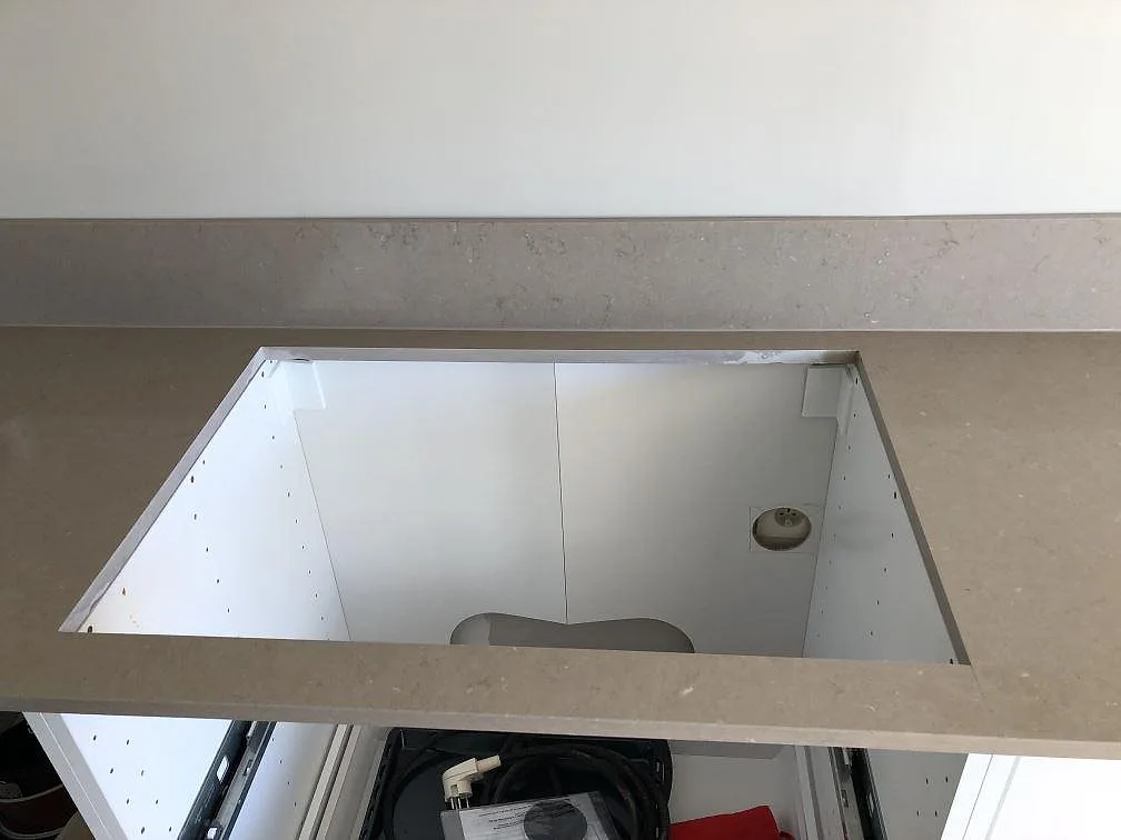 Köksbänkskiva i Silestone Coral Clay ovanifrån med urtag för diskhon över öppen skåpstomme i ett kök i Trelleborg.