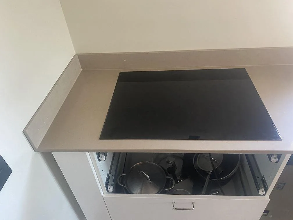 Infälld induktionshäll i polerad Silestone Coral Clay köksbänkskiva i ett kök i Trelleborg.