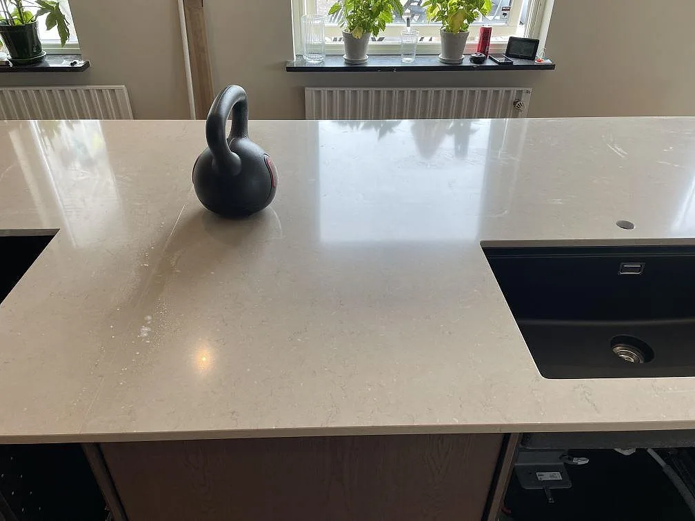 Närbild av polerad Silestone Coral Clay med svart diskho och hällöppning på köksö i Trelleborg.