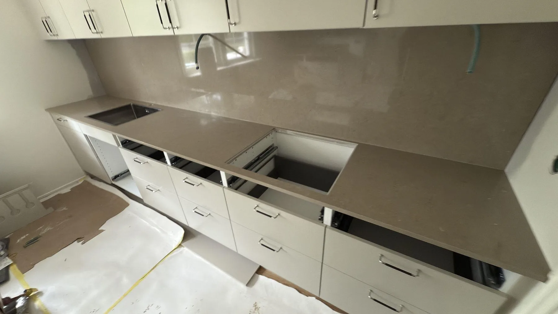 Lång köksbänkskiva i polerad Silestone Coral Clay, kvartskomposit, med öppet hällurtag och matchande väggskiva under överskåp i Tumba.