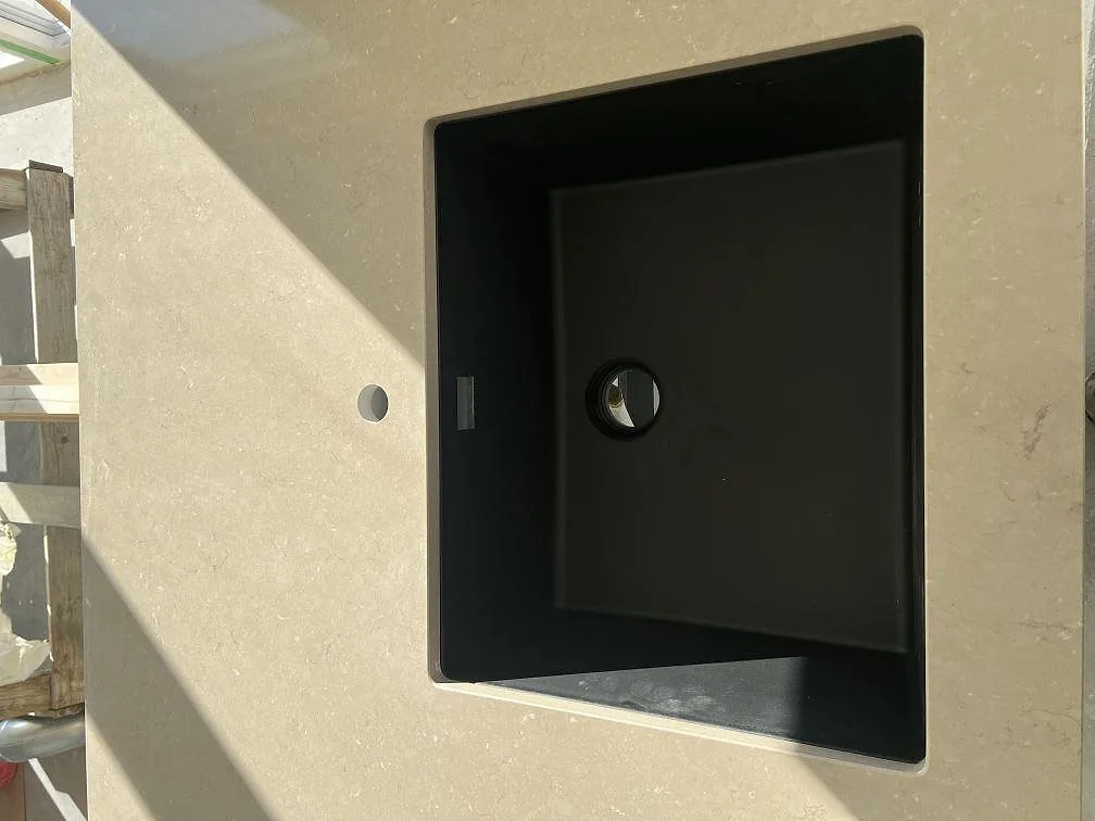 Svart underlimmad diskho i en polerad bänkskiva av Silestone Coral Clay i ett kök i Ucklum.