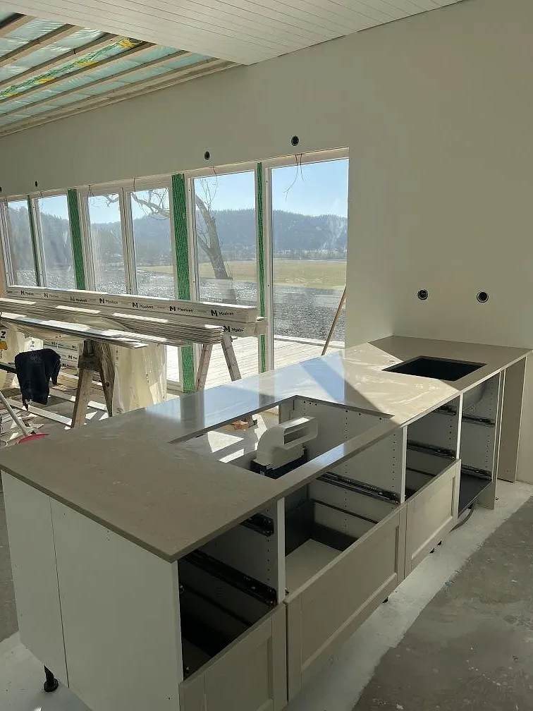 Köksbänkskiva i Silestone Coral Clay, polerad kvartskomposit, på vita köksstommar under montering i Ucklum.