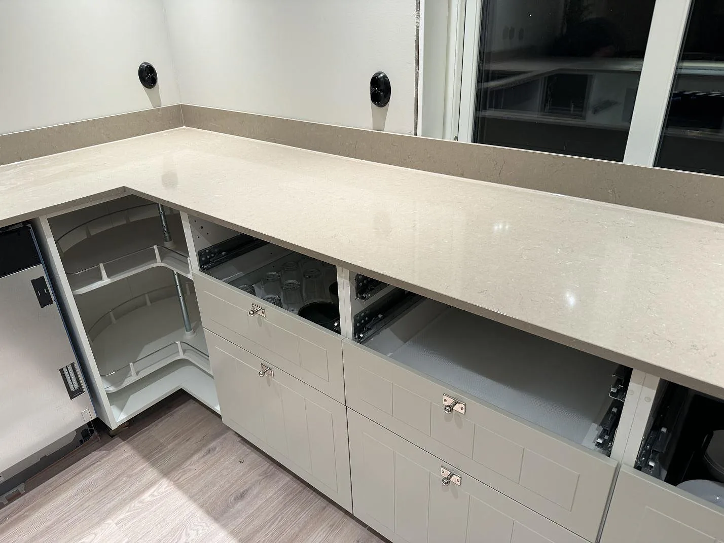 Polerad köksbänkskiva i Silestone Coral Clay med uppvikt stänkkant och vita köksstommar i Uddebo.