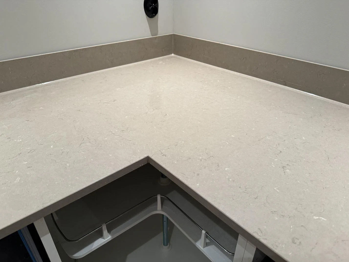 Närbild på L-hörn i polerad Silestone Coral Clay med matchande stänkkant i ett kök i Uddebo.