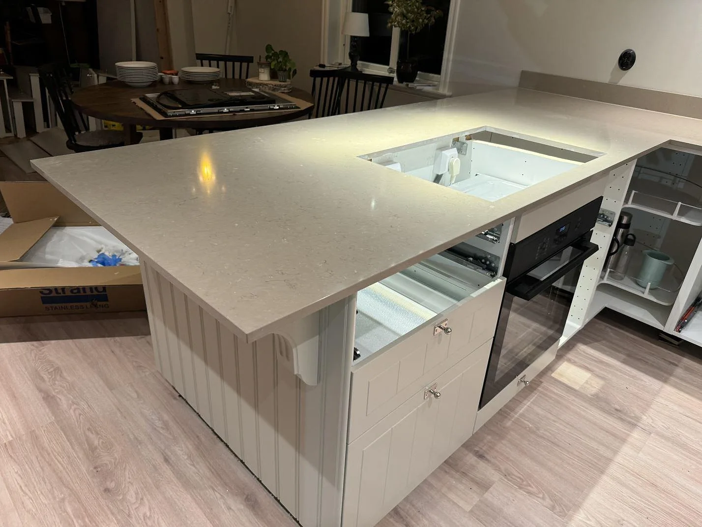 Köksö och L-formad köksbänkskiva i polerad Silestone Coral Clay med hällurtag i ett kök i Uddebo.