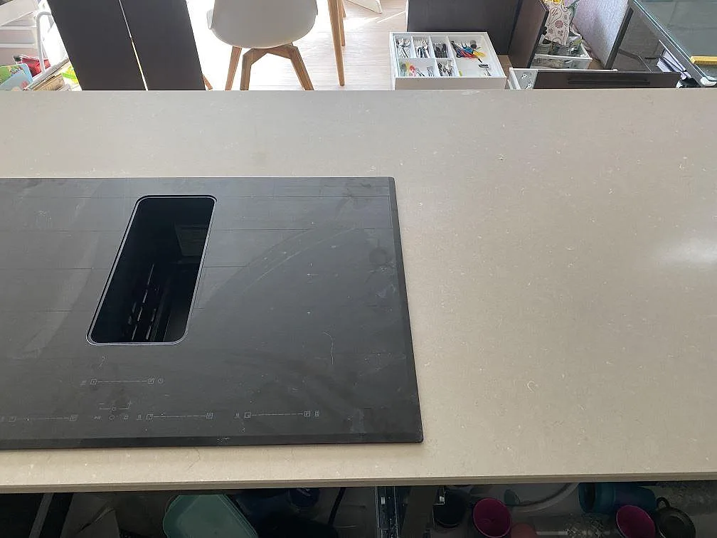Induktionshäll med nedfälld fläkt nedsänkt i en polerad Silestone Coral Clay bänkskiva i ett kök i Uddevalla.