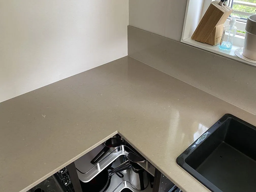 Hörnparti av Silestone Coral Clay bänkskiva i polerad kvartskomposit med fönsterbänk i sten i ett kök i Uddevalla.