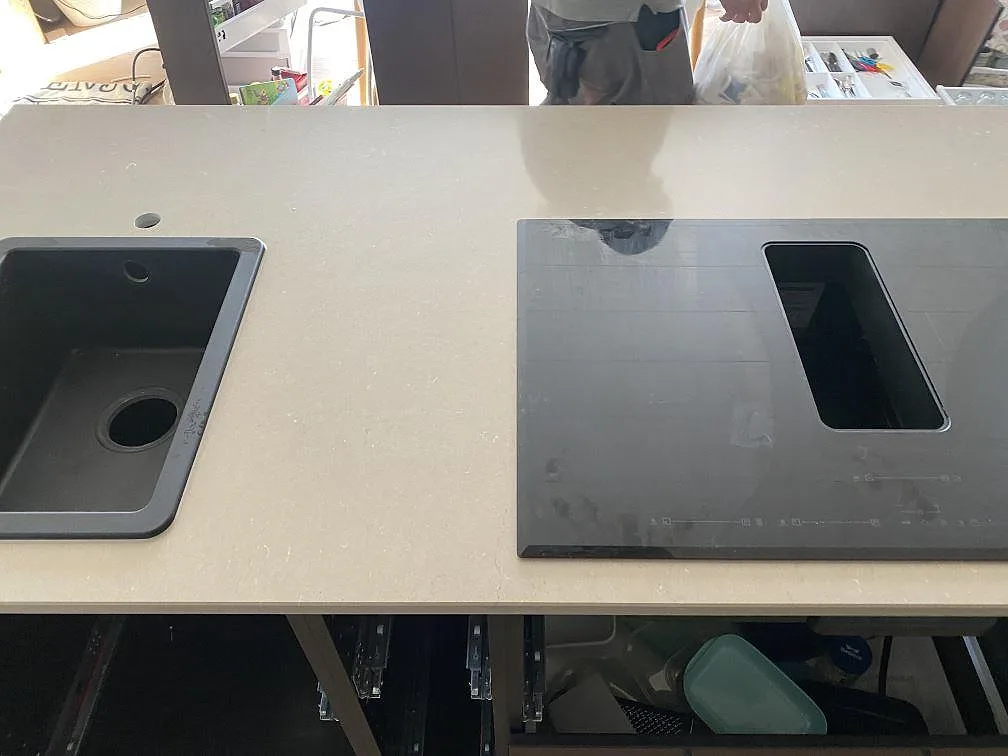 Köksbänkskiva i Silestone Coral Clay, polerad varm greige kvartskomposit, med underlimmad svart kompositdiskho och induktionshäll i ett kök i Uddevalla.