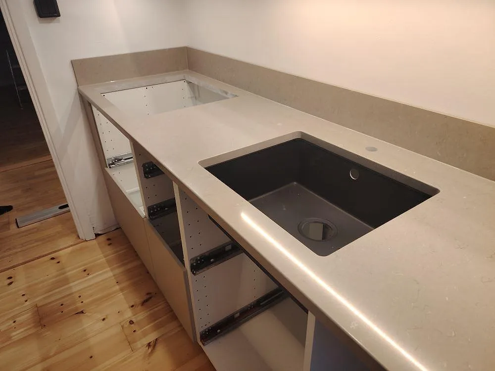 Närbild av polerad Silestone Coral Clay köksbänkskiva med svart underlimmad diskho och hällurtag vid öppna köksstommar i Uppsala.
