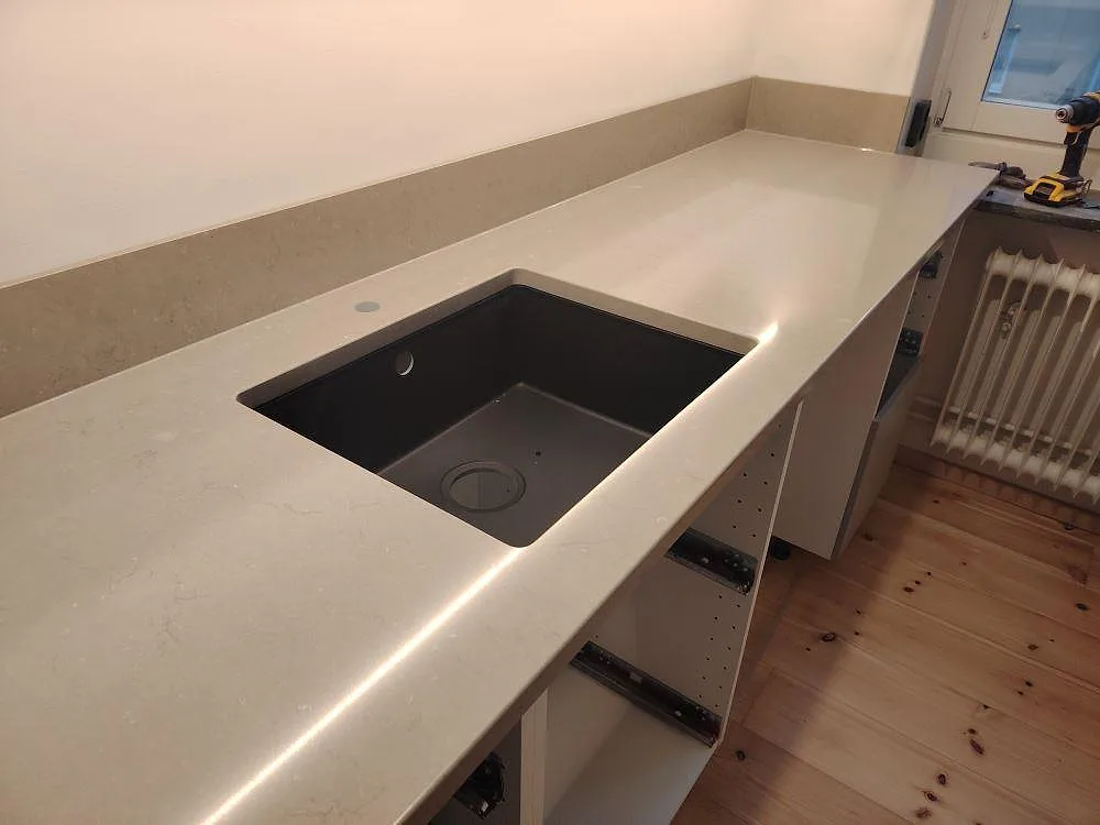 Polerad köksbänkskiva i Silestone Coral Clay med underlimmad diskho, lång arbetsyta och stänkskydd vid fönster i Uppsala.