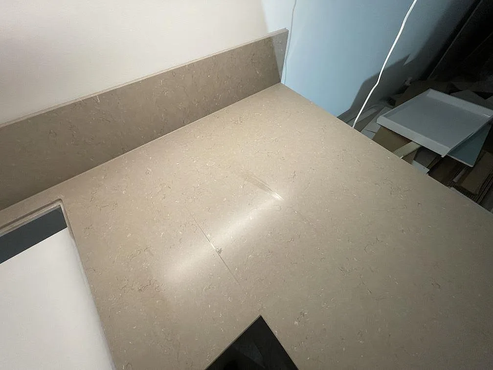 Ytdetalj av matt Silestone Coral Clay med diskret mönstring och uppvikt stänkskydd i ett kök under montering i Uppsala.