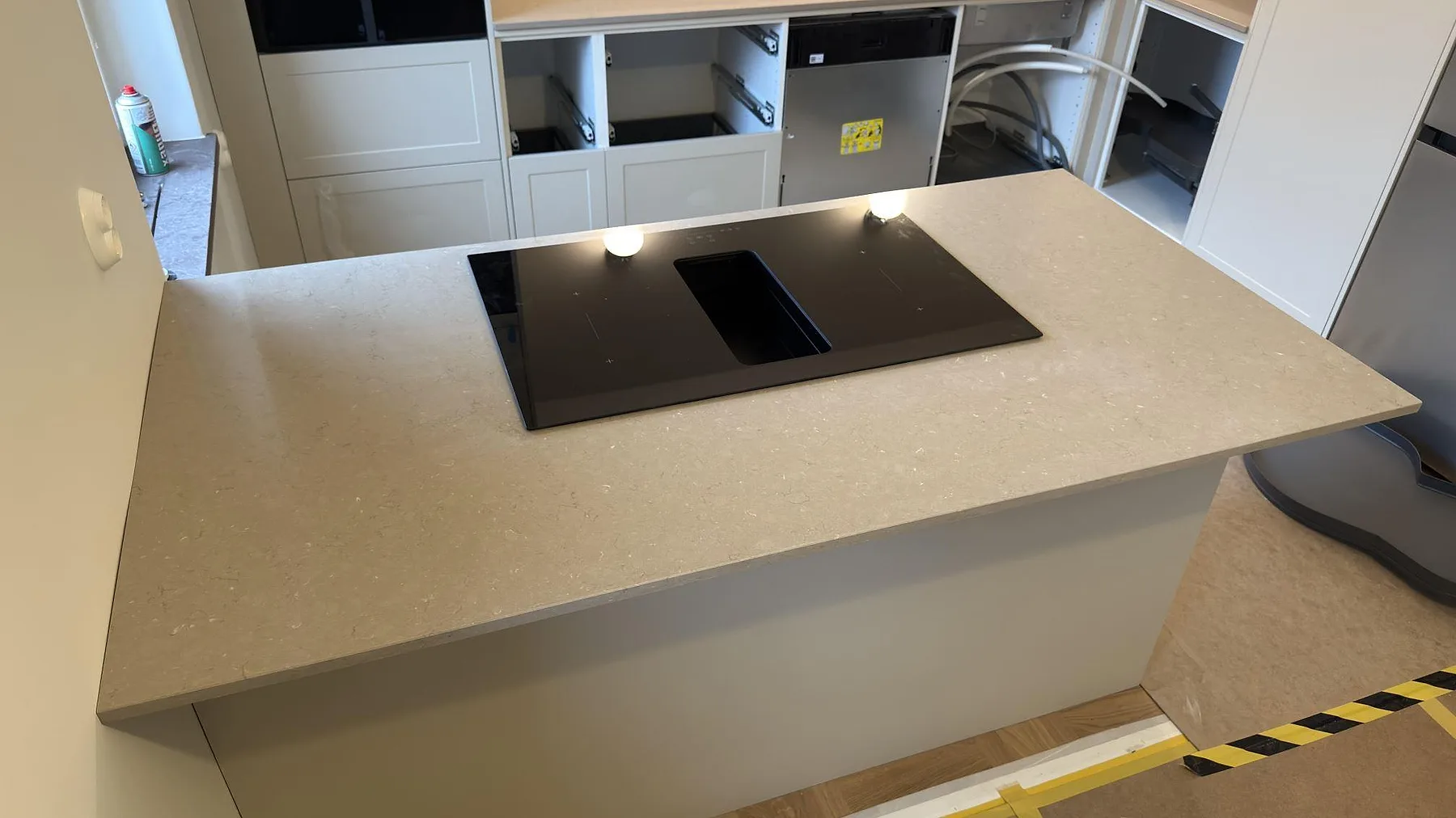 Köksbänkskiva och köksö i beige Silestone Coral Clay komposit, polerad yta med infälld induktionshäll, i ett kök under montering i Uppsala.