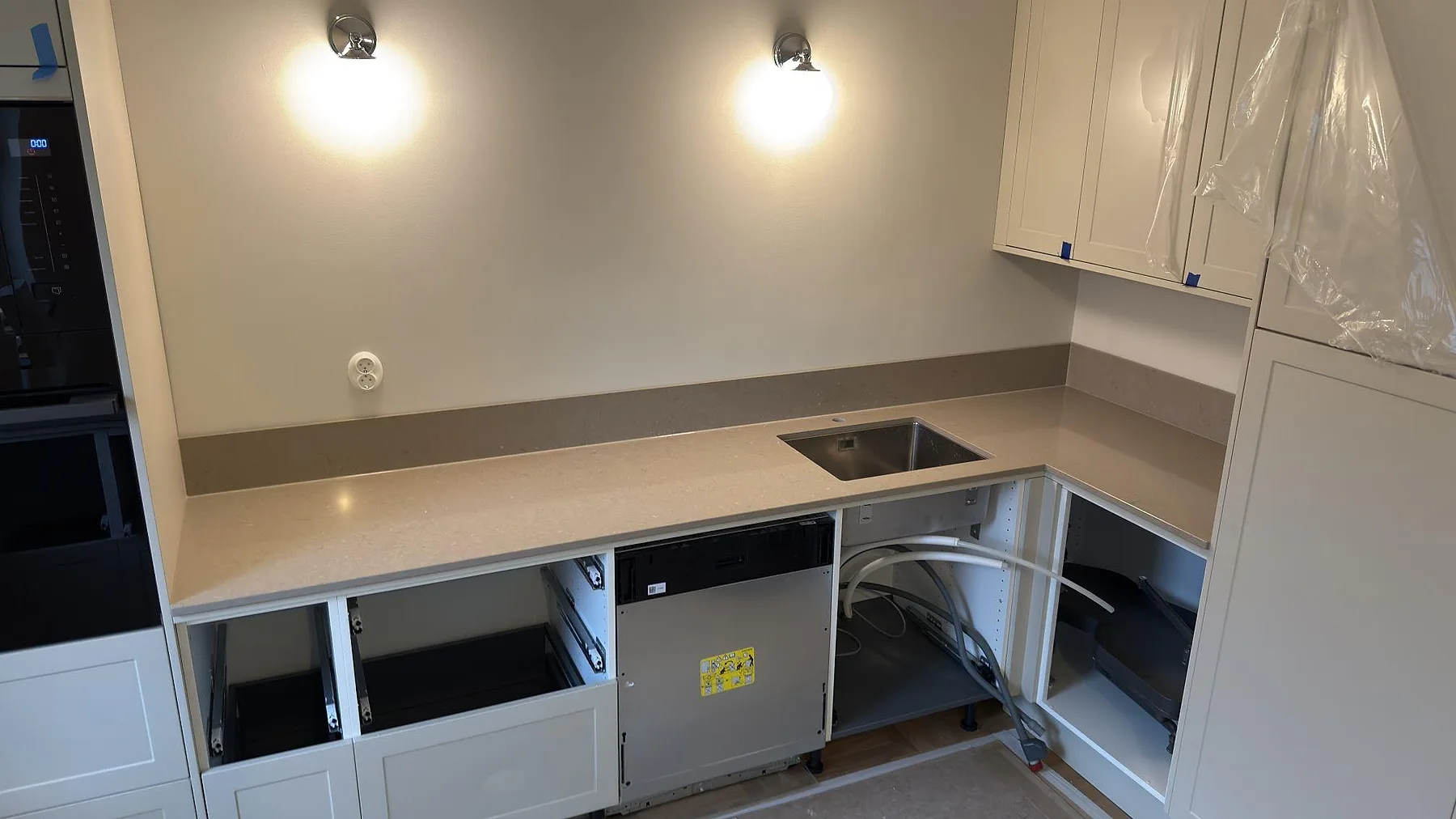 L-formad köksbänkskiva i beige Silestone Coral Clay med underlimmad rostfri diskho och uppvikt stänkkant i samma sten, kök i Uppsala.