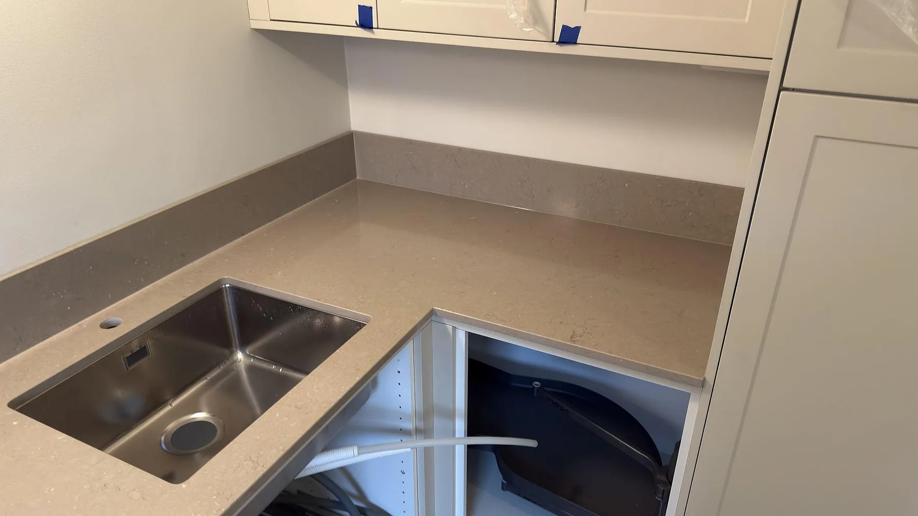 Underlimmad rostfri enkelho i beige Silestone Coral Clay bänkskiva med stänkkant i sten i ett kök i Uppsala.