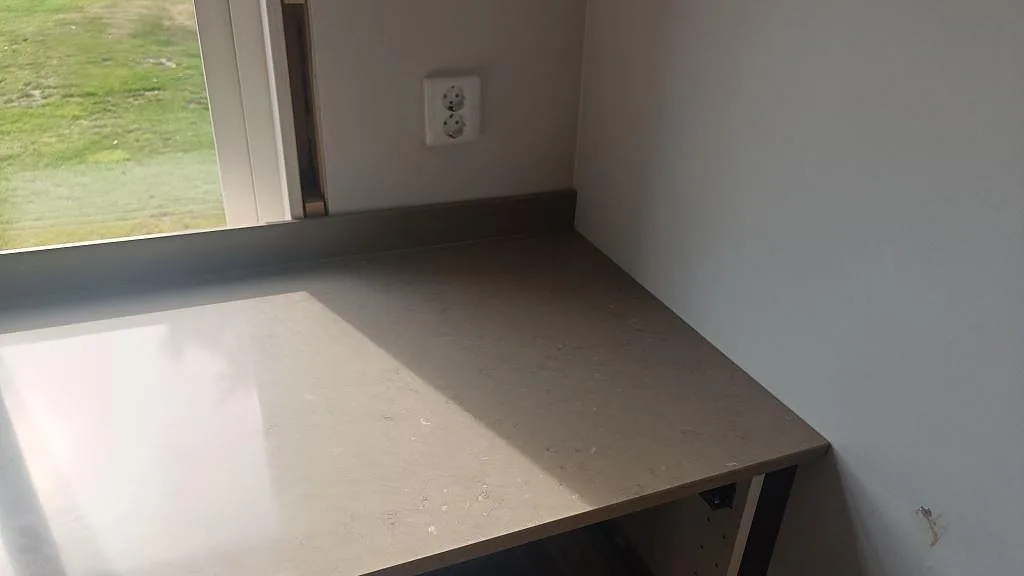 Hörnsektion av köksbänkskiva i Silestone Coral Clay, polerad gråbeige kvartskomposit med stänkskydd i väckelsång.