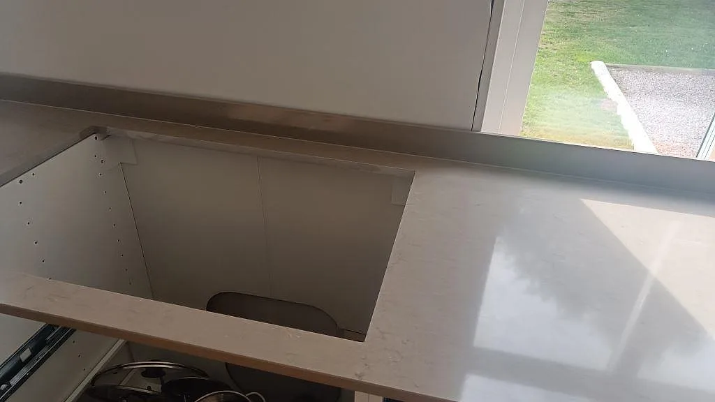 Detalj av rektangulärt urtag i polerad Silestone Coral Clay bänkskiva med 12 mm stänkskydd och öppna stommar i väckelsång.