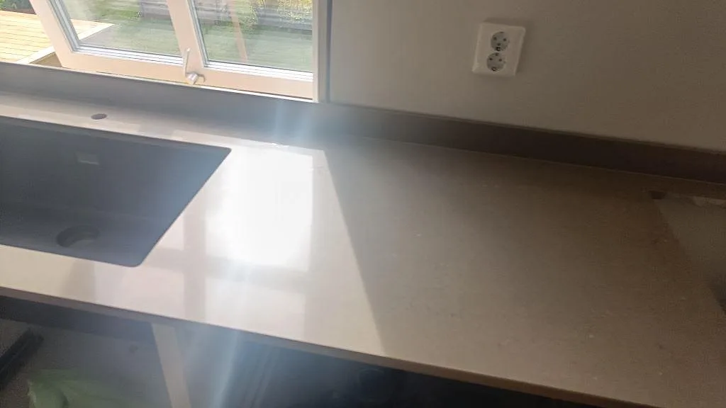 Polerad Silestone Coral Clay vid svart diskho och stänkskydd, fotograferad under köksmontering i väckelsång.
