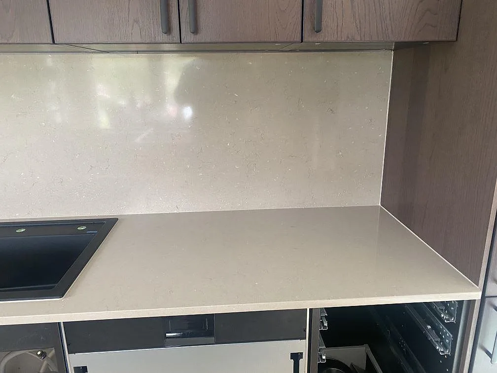 Närbild på bänkskiva och uppdraget stänkskydd i polerad Silestone Coral Clay med svart diskho, kök i Väröbacka.