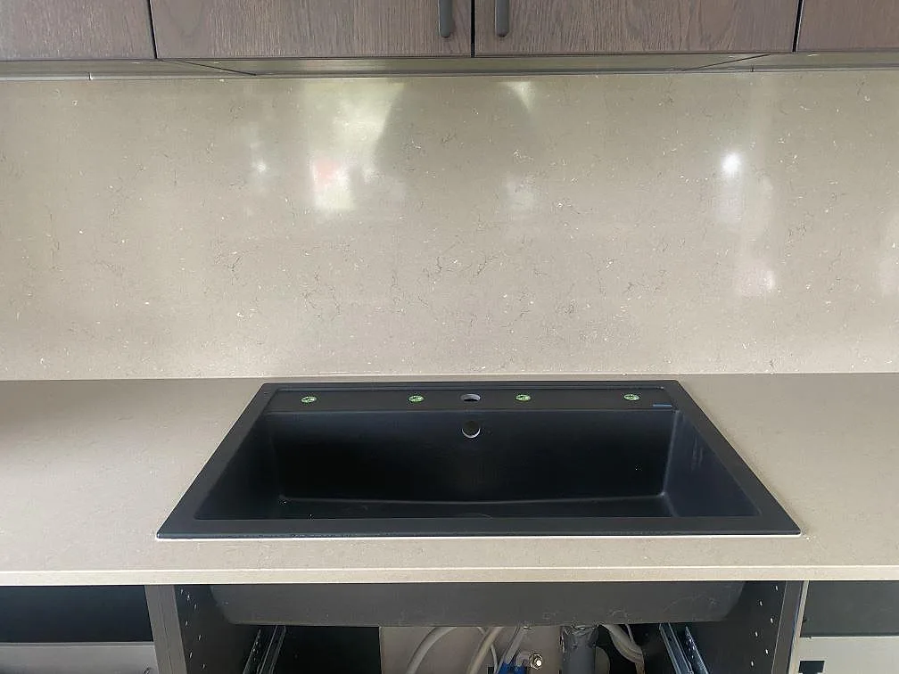 Svart underlimmad kompositdiskho i polerad Silestone Coral Clay bänkskiva med stänkskydd i samma sten, kök i Väröbacka.