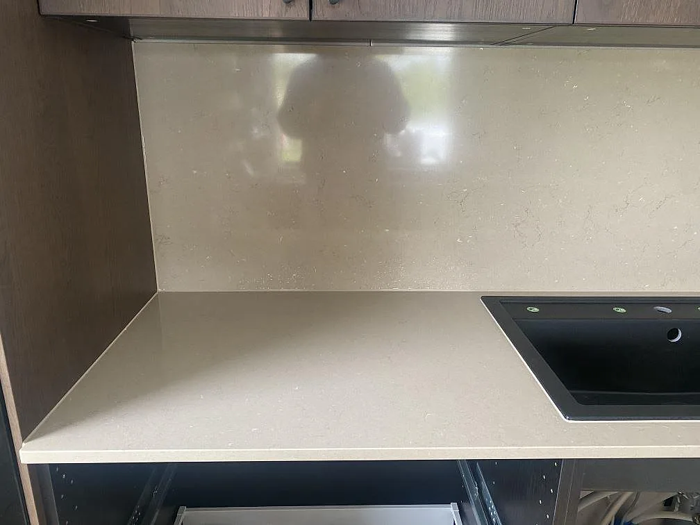 Polerat stänkskydd och bänkskiva i Silestone Coral Clay med svart underlimmad diskho i ett kök i Väröbacka.