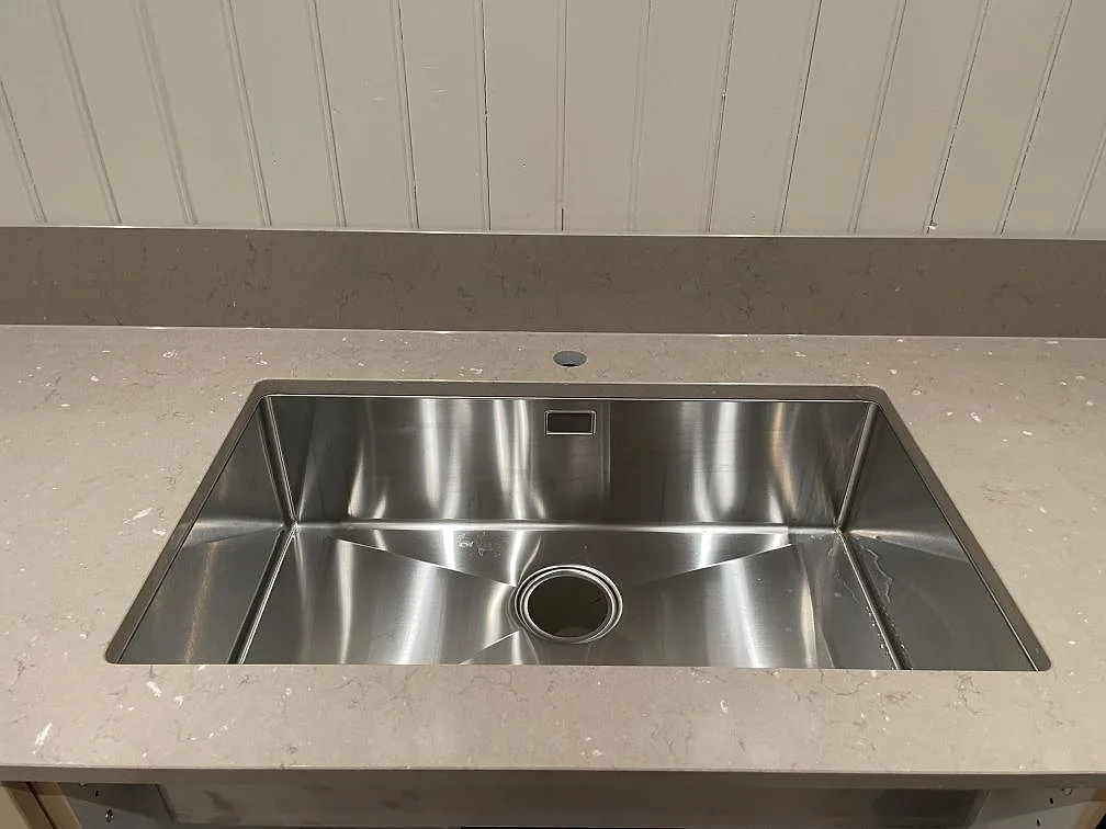 Närbild på underlimmad rostfri diskho i en beige Silestone Coral Clay köksbänkskiva i Västerås.