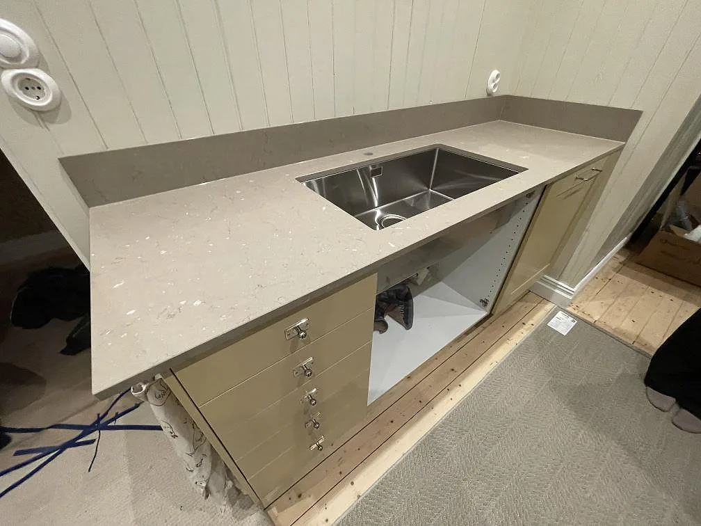 Lång köksbänkskiva i Silestone Coral Clay med diskho och lådhurts under montering i ett kök i Västerås.