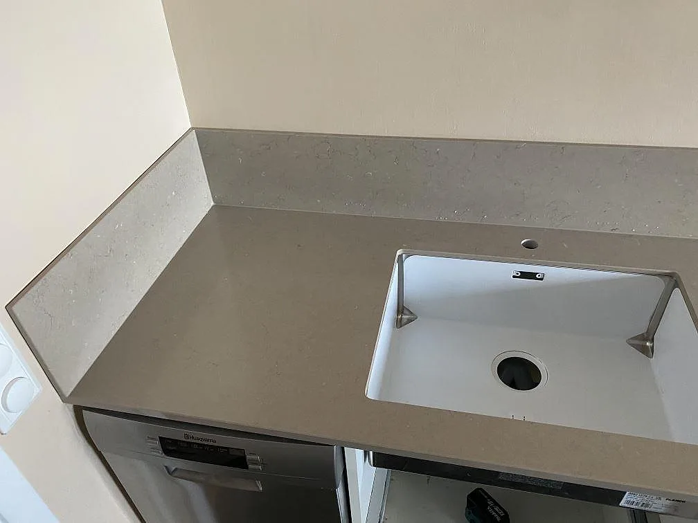 Polerad kompositbänkskiva i Silestone Coral Clay med diskhoöppning och matchande stänkskydd i Västra Frölunda.