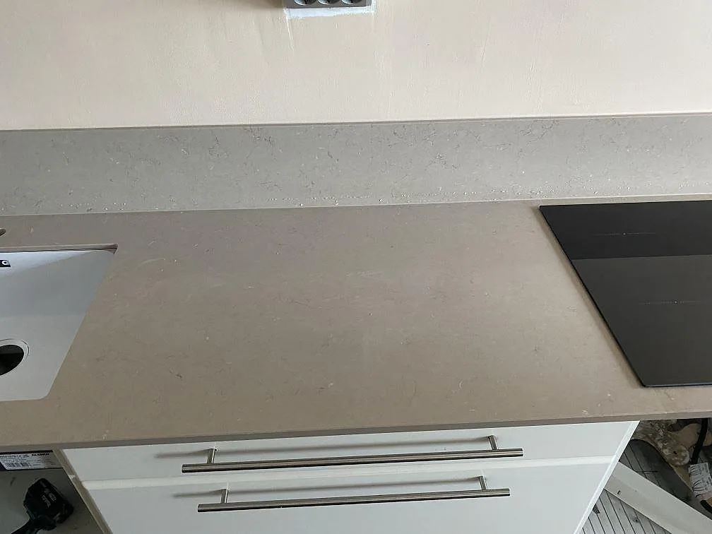 Polerad Silestone Coral Clay-bänkskiva mellan diskho och häll med vita kökslådor i Västra Frölunda.