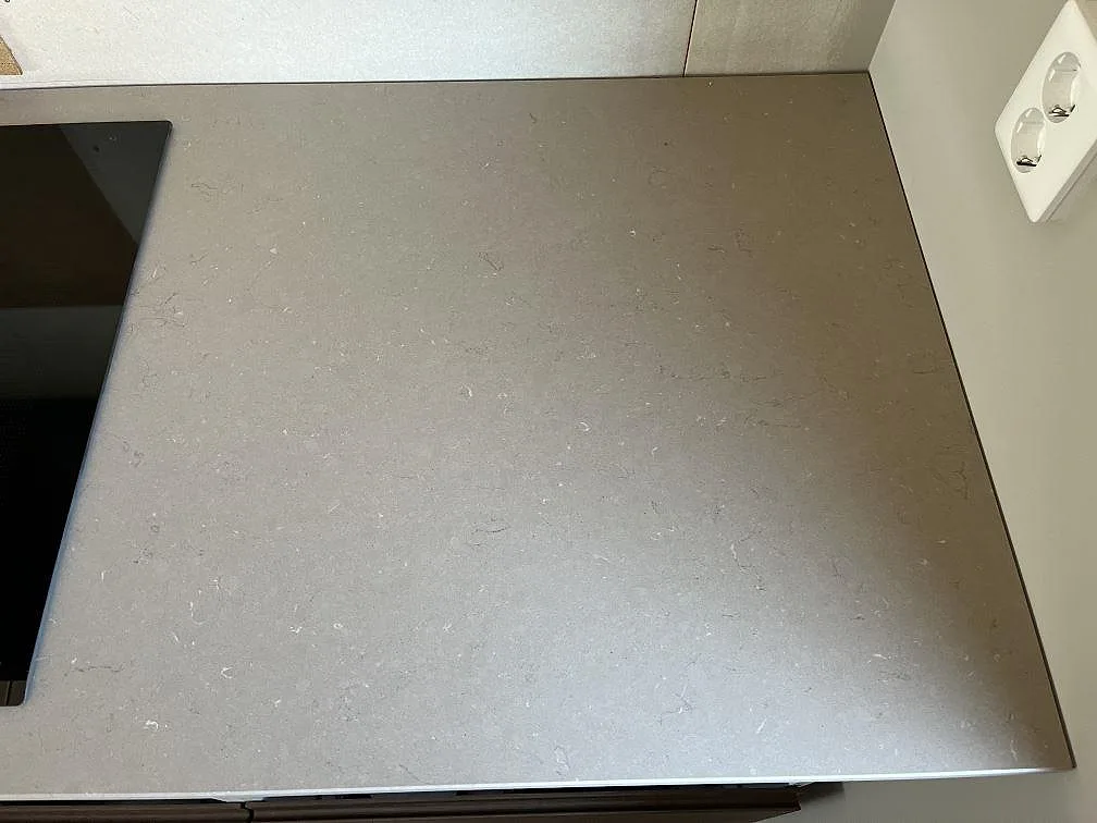 Bänkskiva i Silestone Coral Clay med infälld induktionshäll och vägguttag, matt greige yta i ett kök i Växjö.