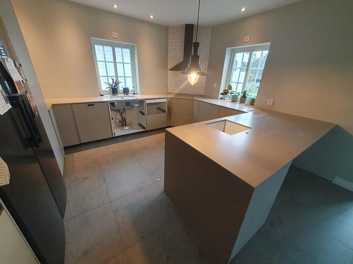 Kök under montering med Silestone Coral Clay komposit på bänkar och köksö samt synlig diskho i Vallentuna.