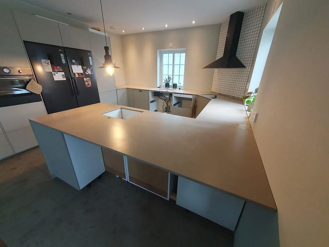Bred köksvy med gråbeige Silestone Coral Clay som bänkskivor och köksö, matt Mocka-yta, i Vallentuna.
