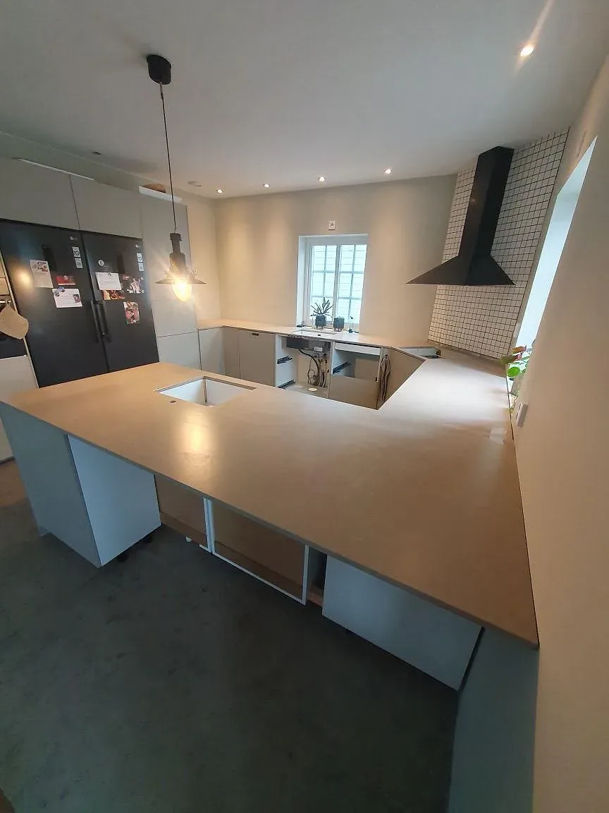 Sidovy av monterad köksö och bänkskivor i Silestone Coral Clay komposit med matt Mocka-finish i Vallentuna.