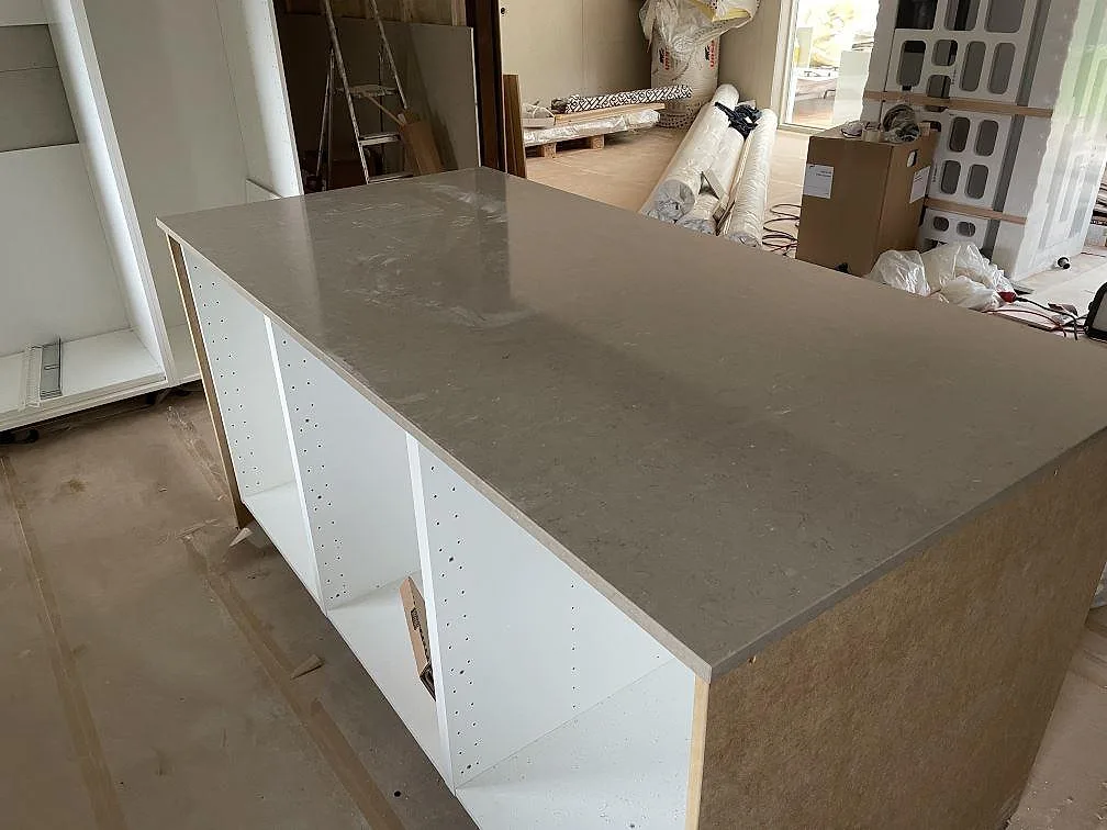 Köksö med polerad Silestone Coral Clay i varm gråbeige komposit under montering i Varberg.