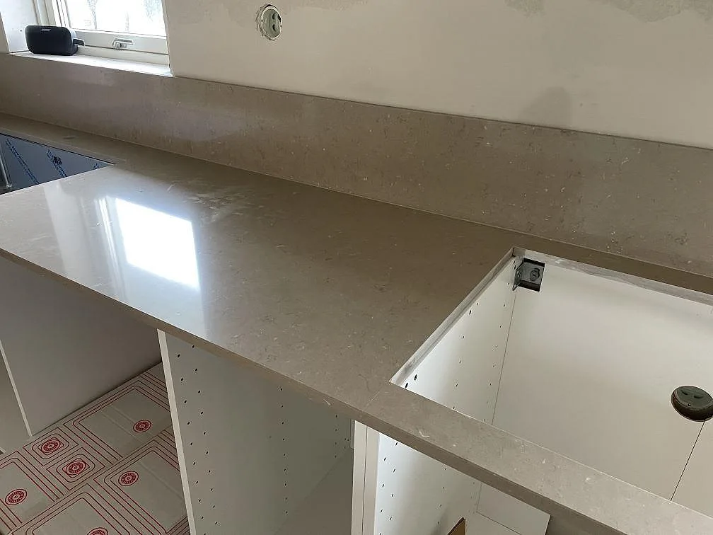 L-formad köksbänkskiva i polerad Silestone Coral Clay med stänkkant och stor urtagning i Varberg.
