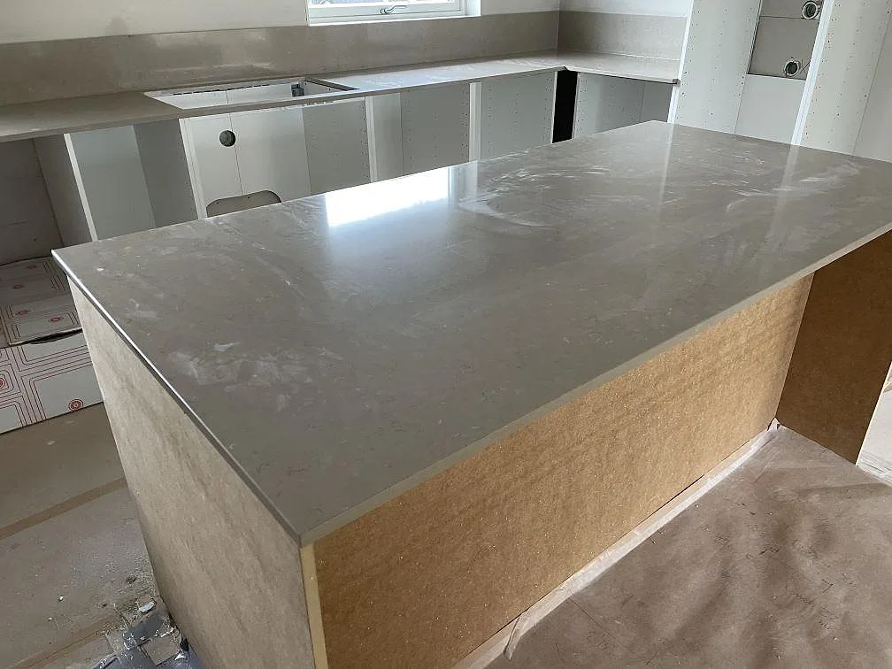 Polerad köksö i Silestone Coral Clay med L-formad bänkskiva och stänkkant i ett kök i Varberg.