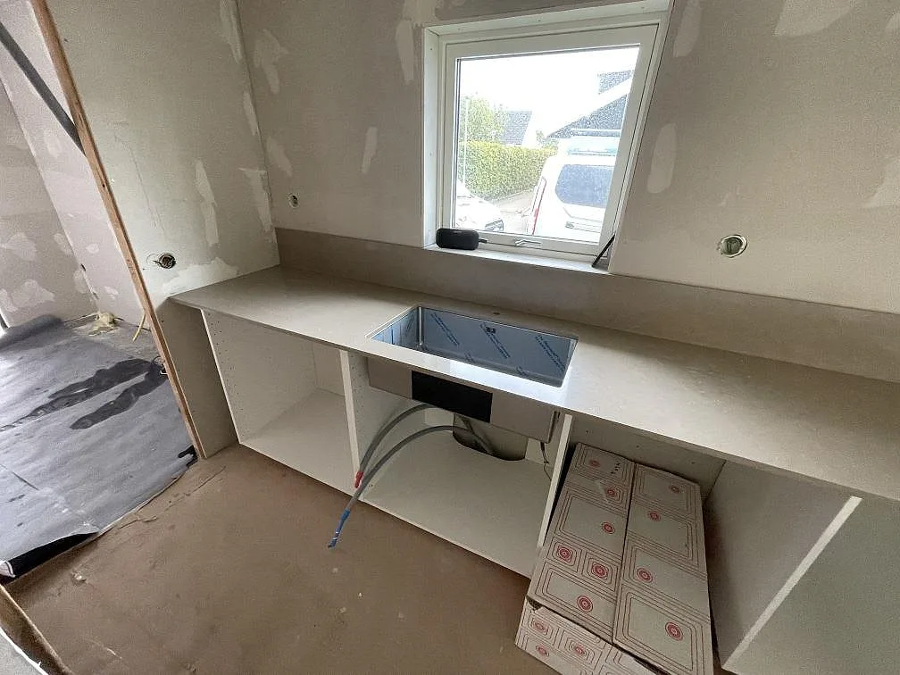 Köksbänkskiva i polerad Silestone Coral Clay med diskbänksdel under montering vid fönster i Varberg.