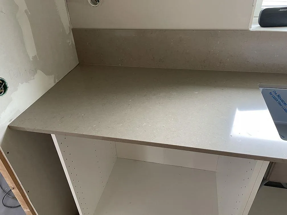 Polerad bänkskiva i Silestone Coral Clay med låg stänkkant och öppna köksstommar i Varberg.