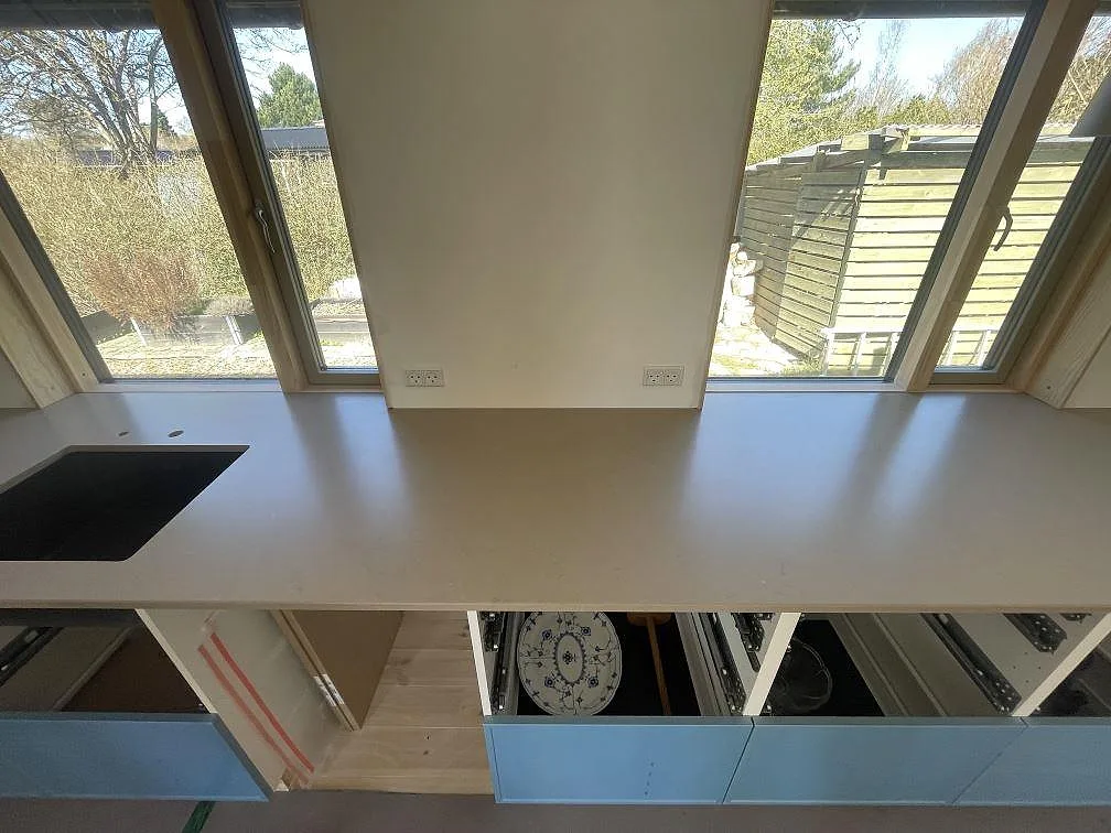 Köksbänkskiva i Silestone Coral Clay sedd ovanifrån med den svarta fyrkantiga diskhon och borrade blandarhål i ett kök i Vejby Strand.