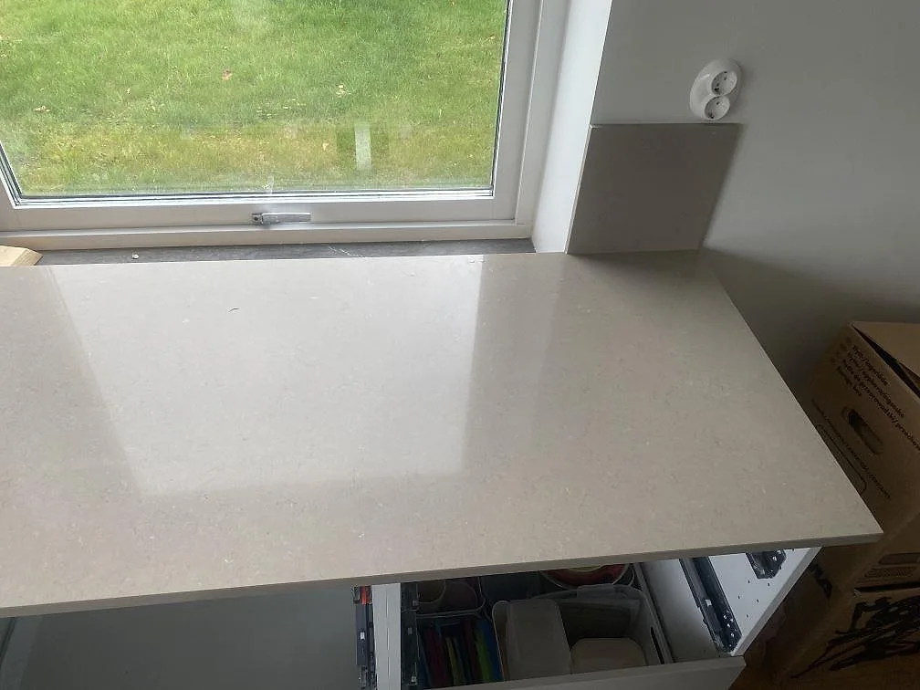 Köksbänkskiva i greige Silestone Coral Clay vid fönstret med fönsterbänk i samma sten i ett kök i Vellinge.