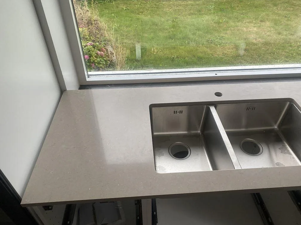 Underlimmad rostfri dubbeldiskho i en köksbänkskiva av Silestone Coral Clay i Vellinge, sedd snett uppifrån.